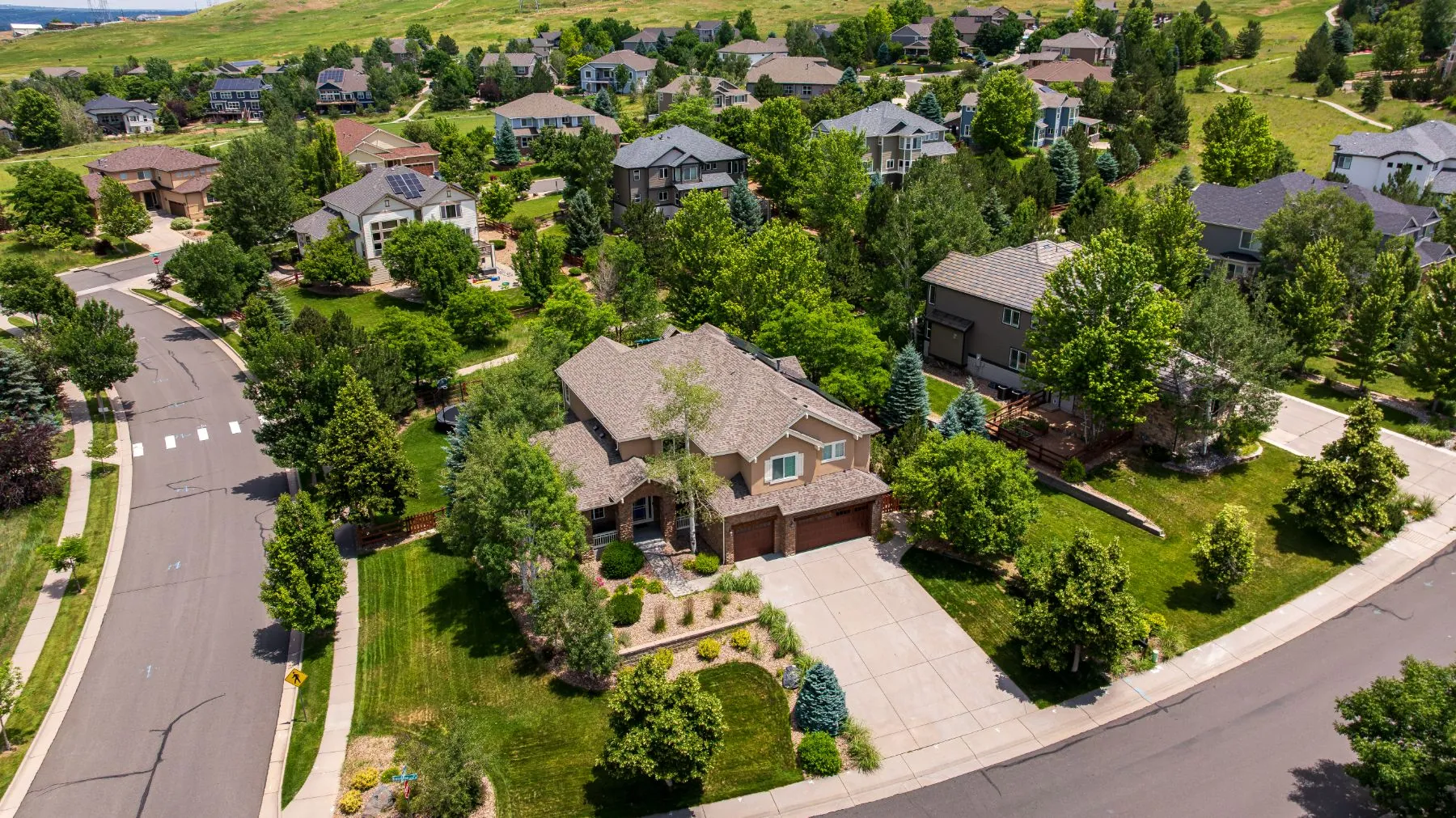 Aerial view of a Colorado foothills neighborhood with rooftop solar on several homes